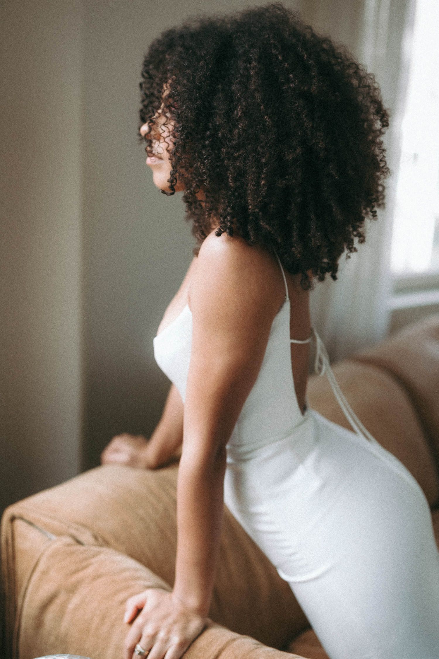 Elegant bridal boudoir session featuring a white dress and natural curls.