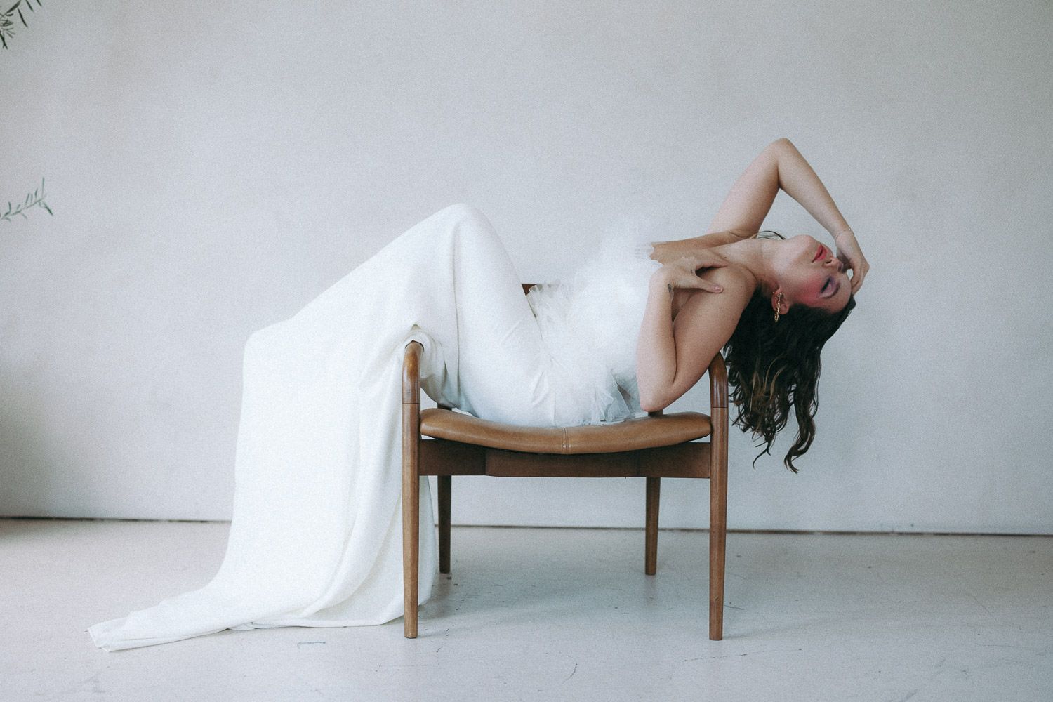 Minimalist bridal photo series with flowing white fabric and wooden chair.
