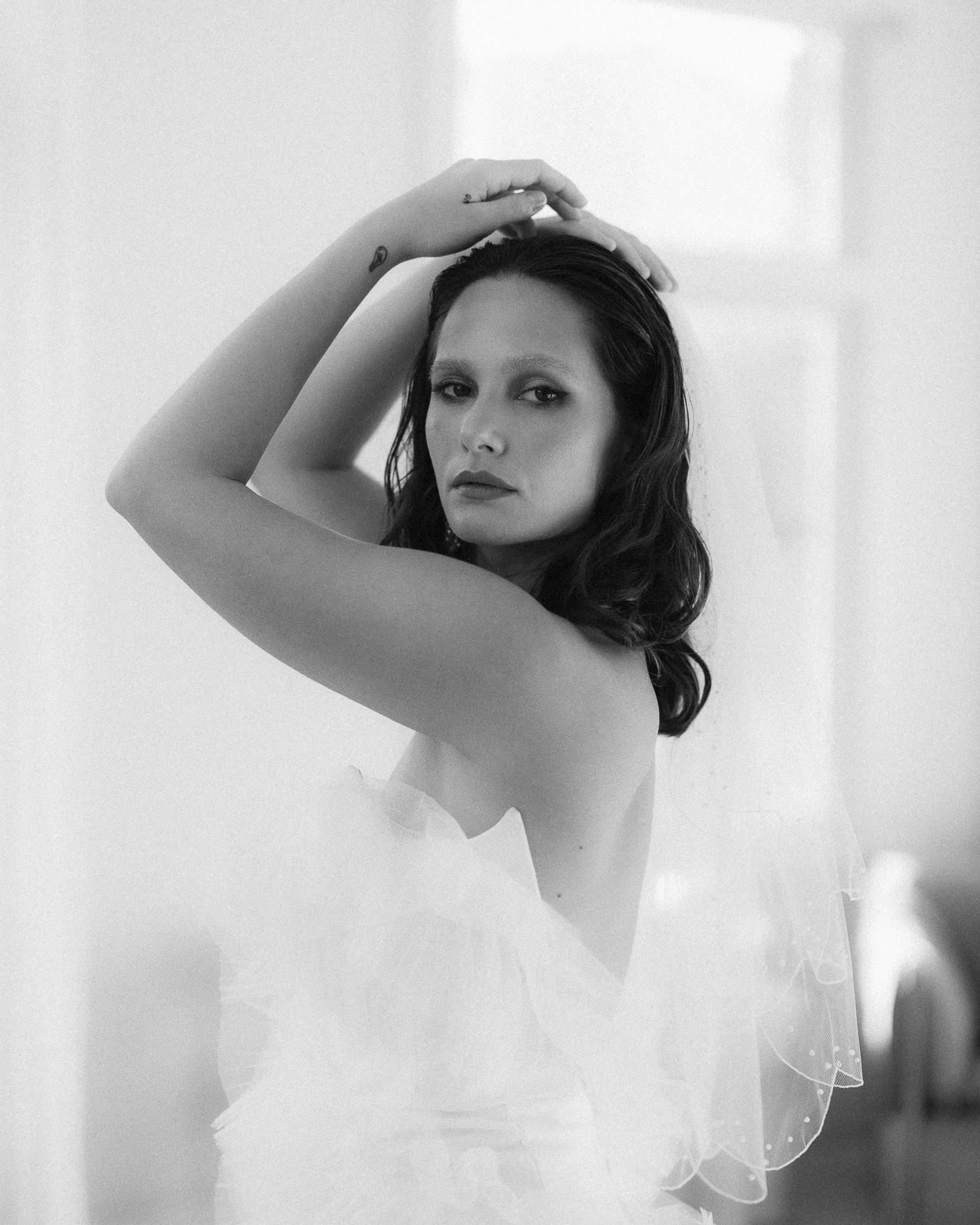 Artistic black and white bridal portrait with dramatic window lighting.