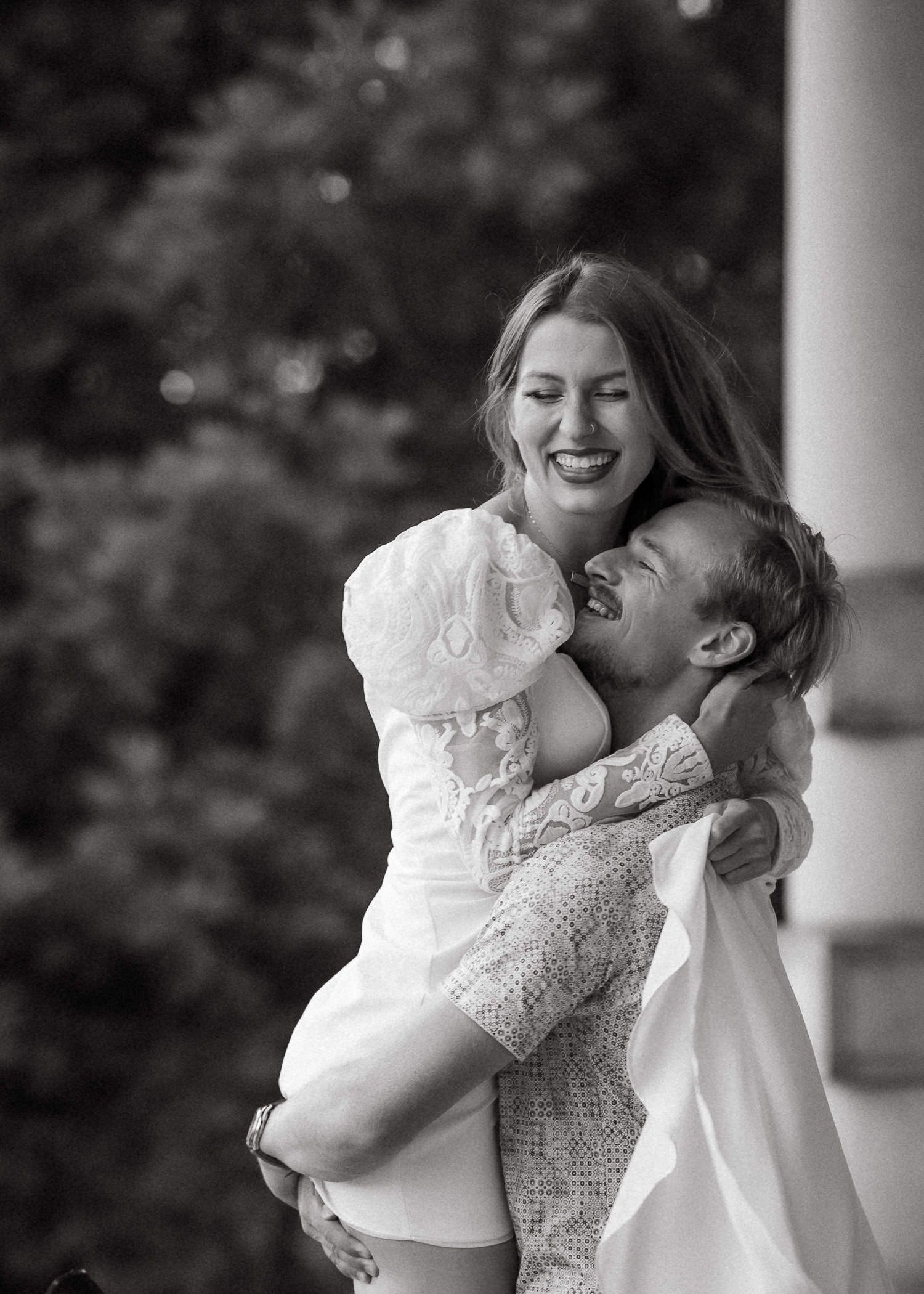 Joyful couple sharing intimate moments near white columns outdoors.