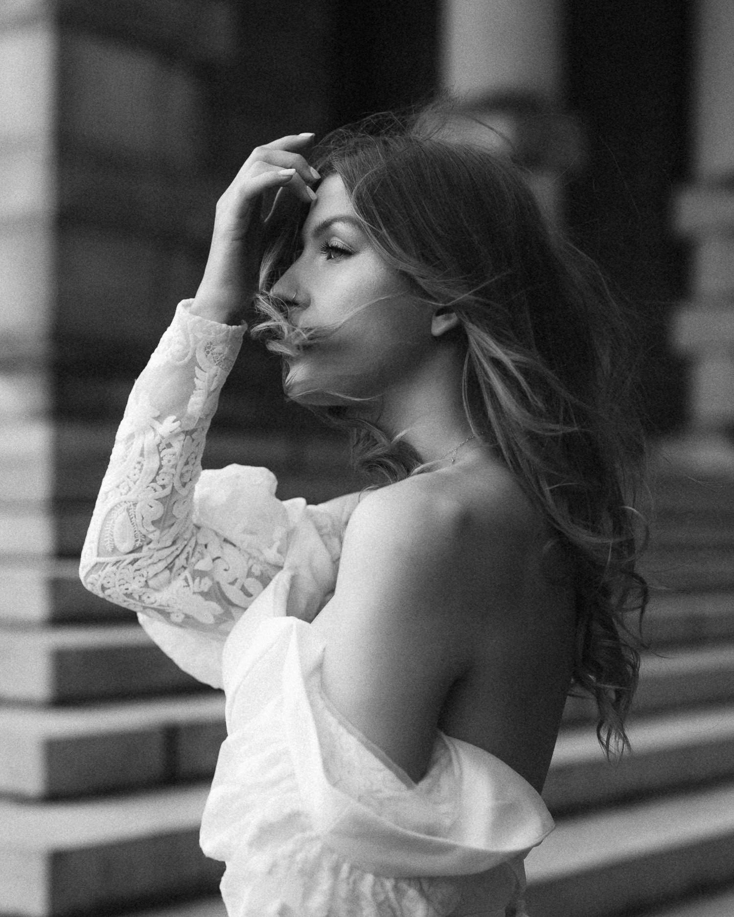 Elegant black and white portrait series featuring a white lace dress against architectural elements.