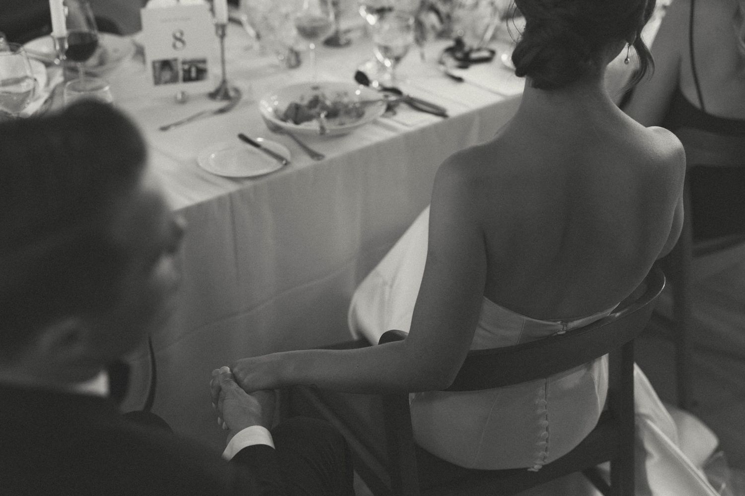 A black and white photo of wedding guests seated at a reception dinner table.