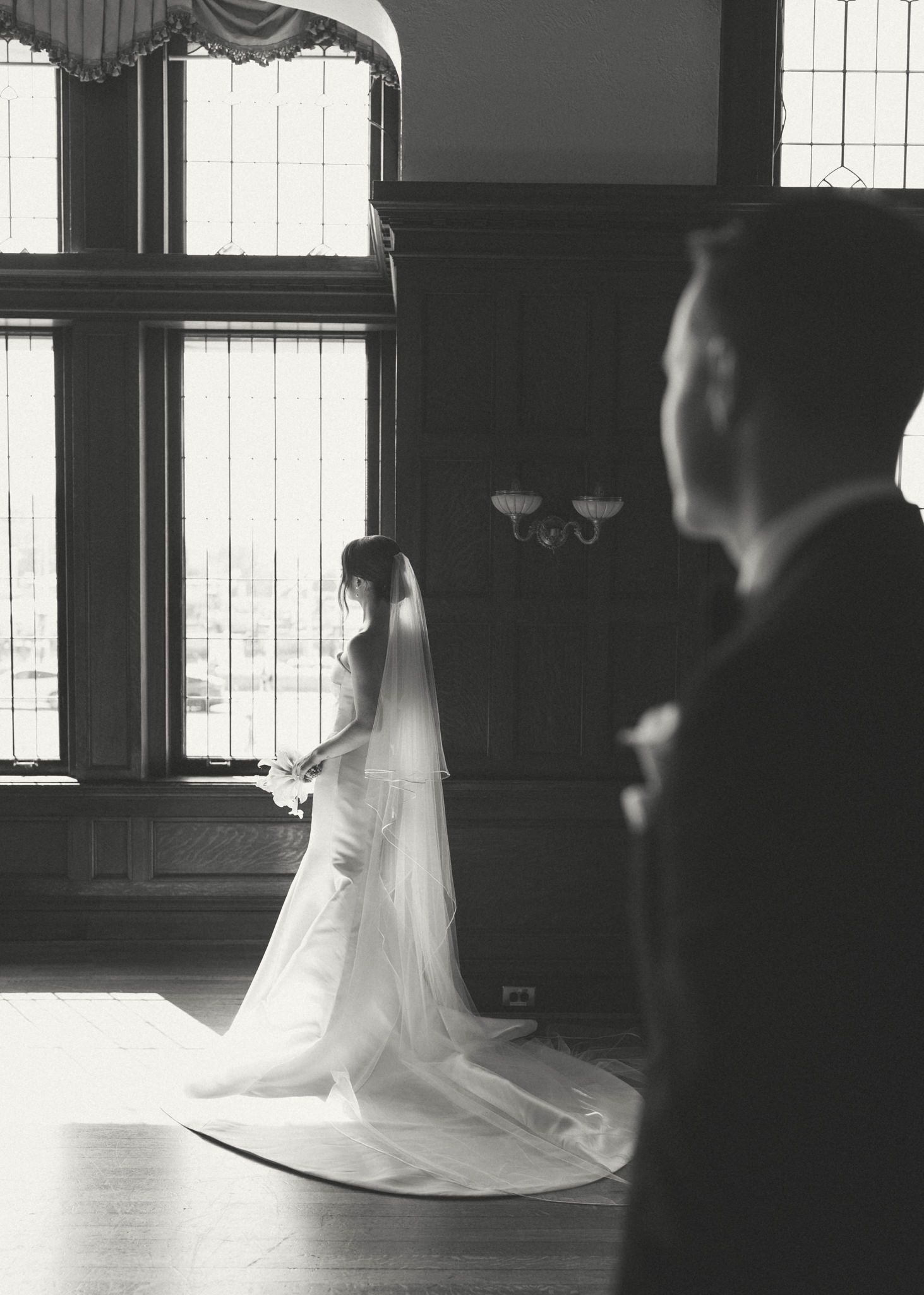 Silhouettes dancing near bright windows in formal venue.