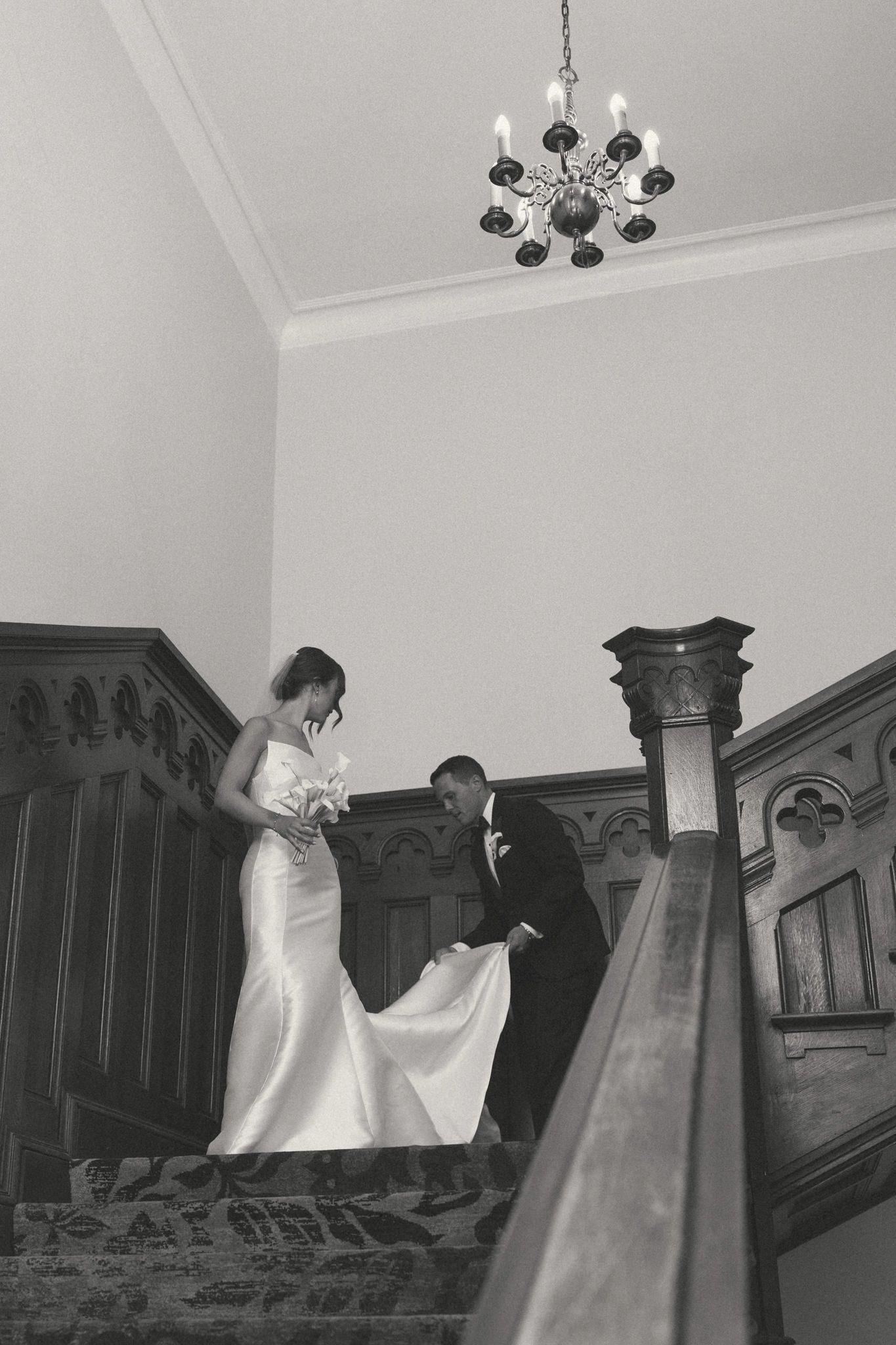 Elegant staircase scene with flowing white dress in black and white.