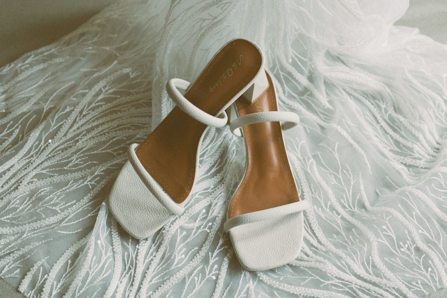 Elegant white bridal shoes displayed on soft white fur background.