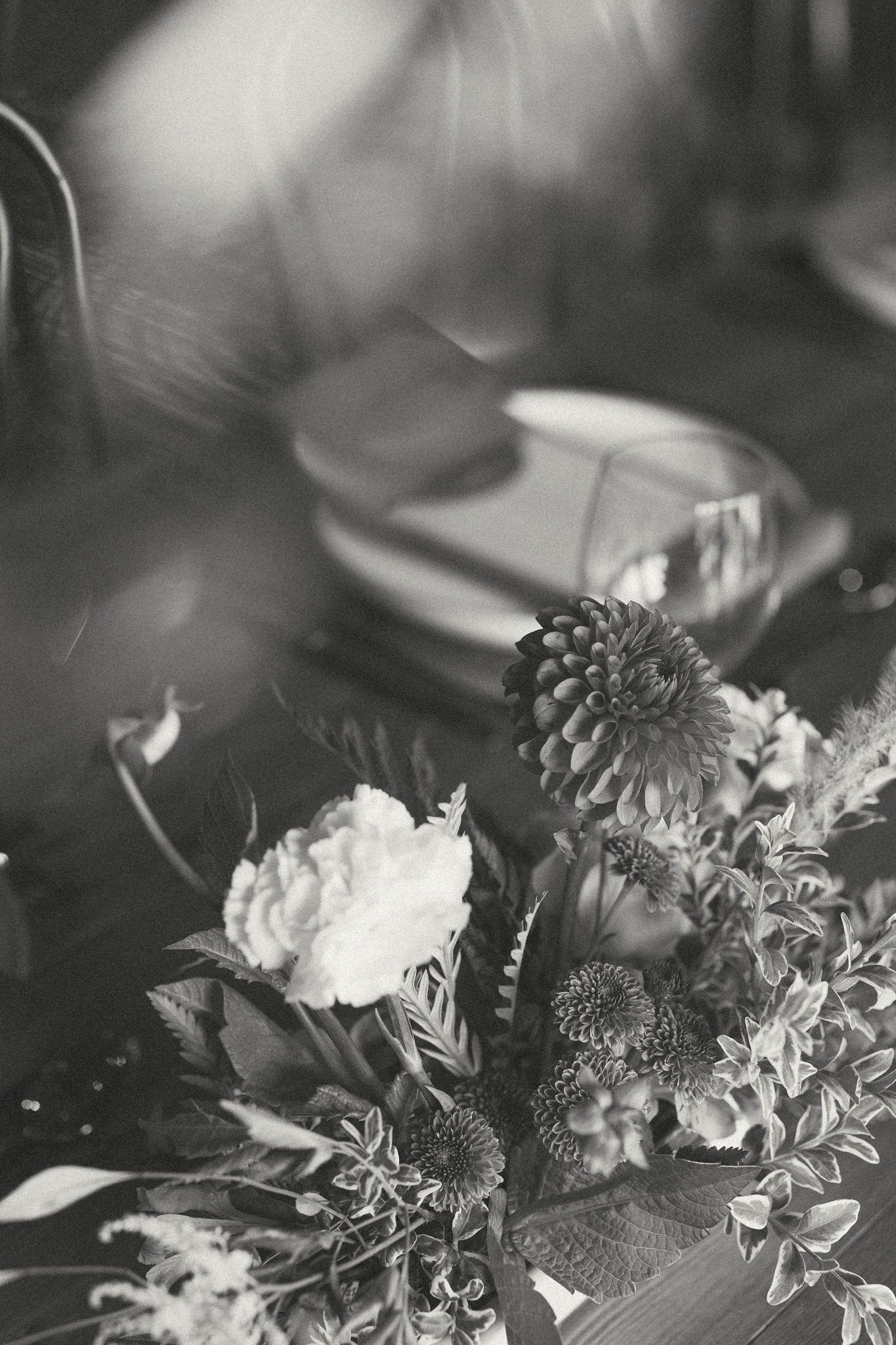 Black and white artistic photo of wedding floral arrangement with delicate blooms and greenery.