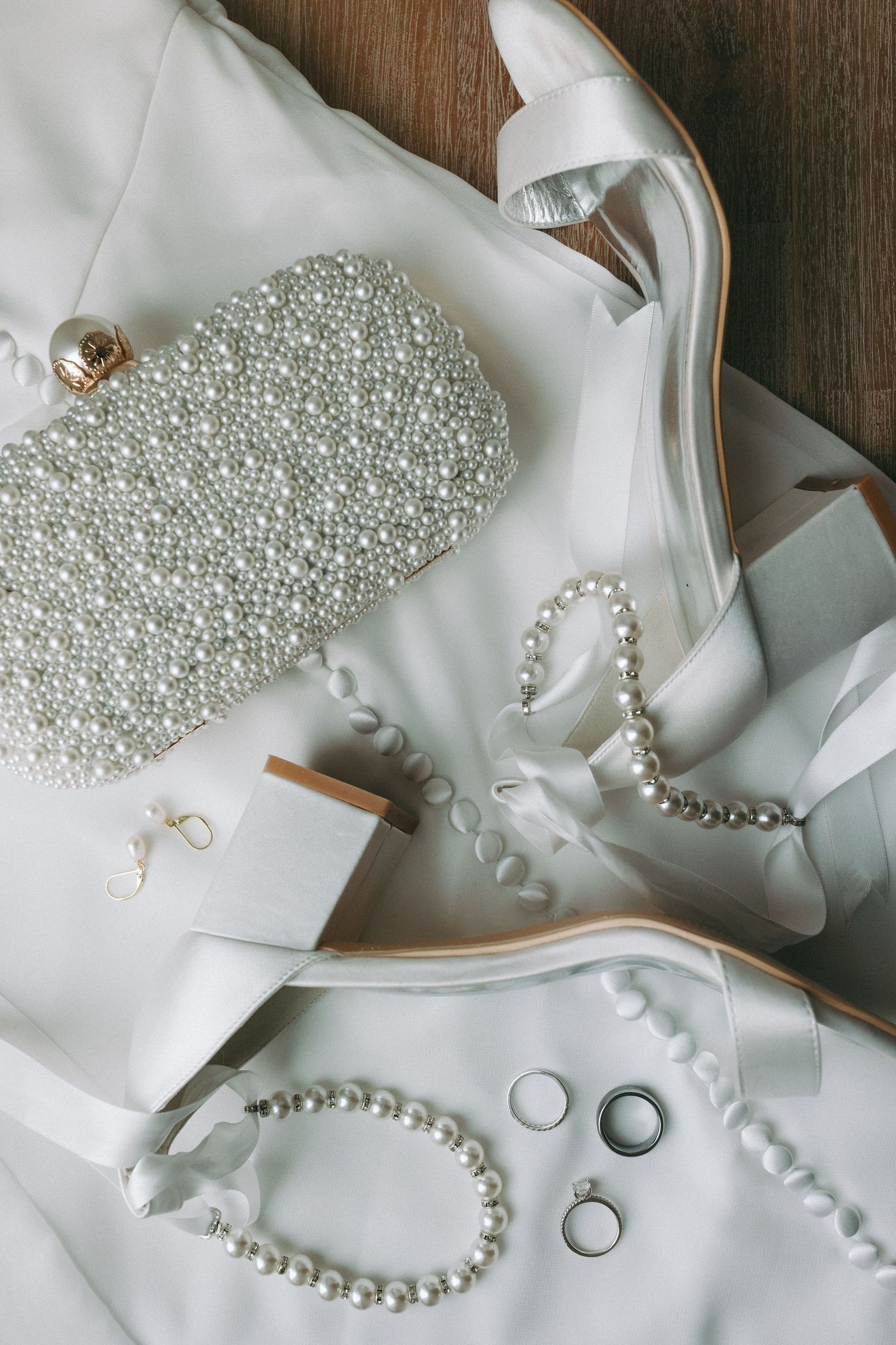 Flat lay detail shot of a bride's purse, shoes, bracelet and rings.