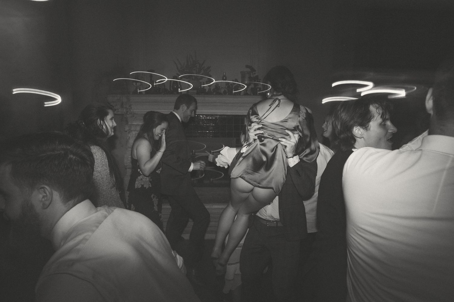 Silhouettes of wedding guests dancing under swirling light patterns.