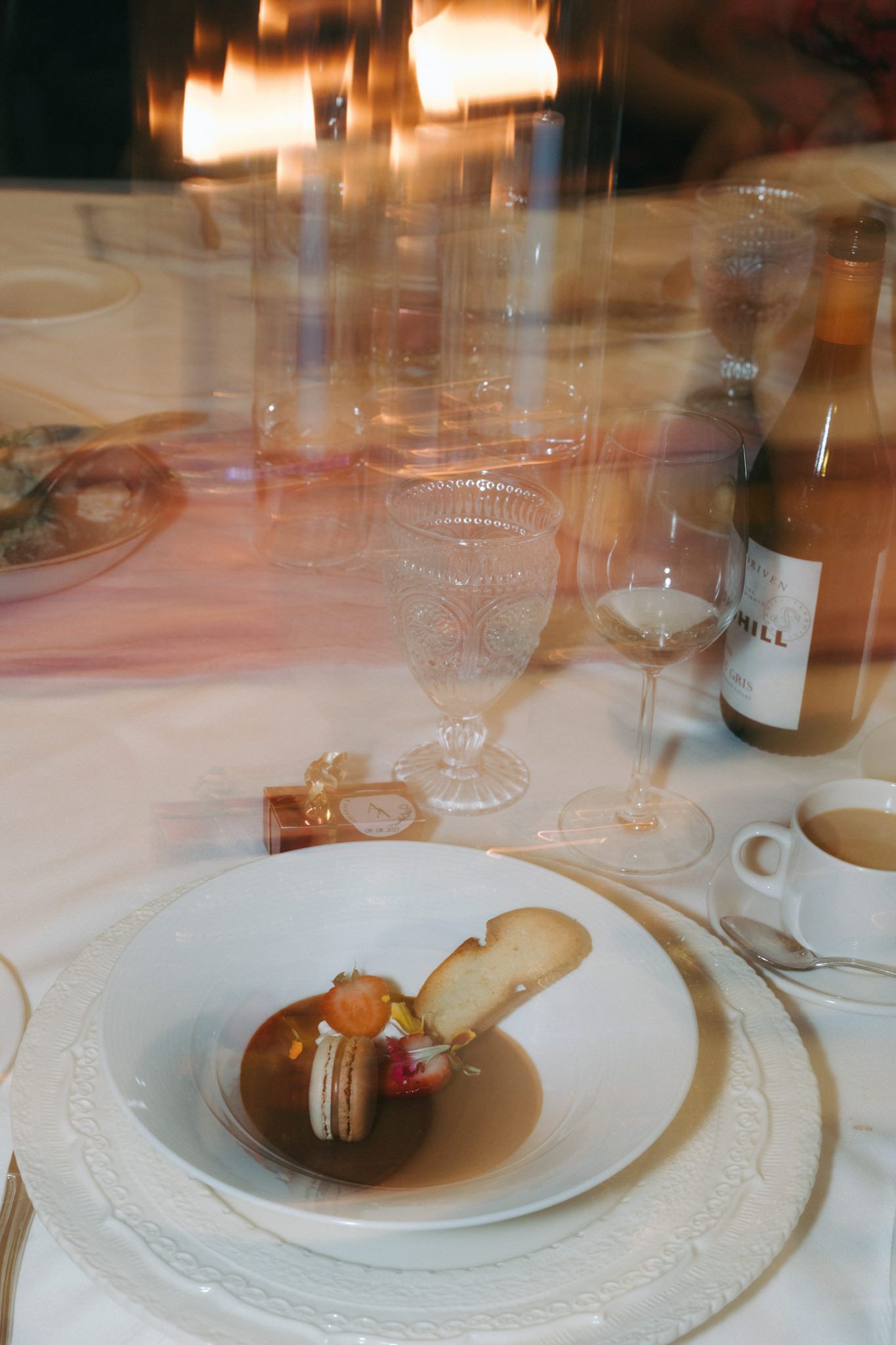 Fine dining place setting with white plates and wine glasses on an elegant table.