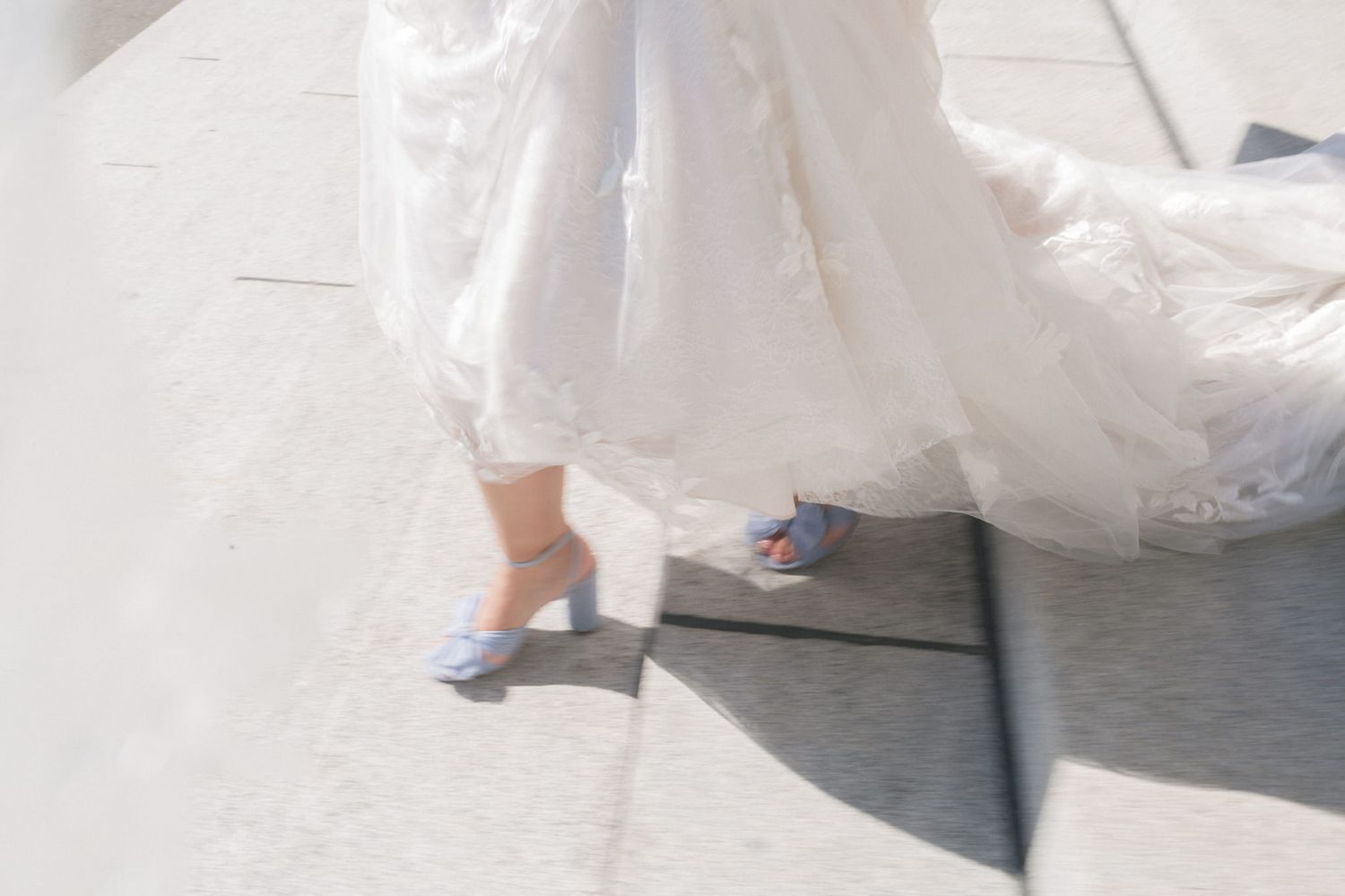 Flowing white wedding dress train trailing on stone steps.
