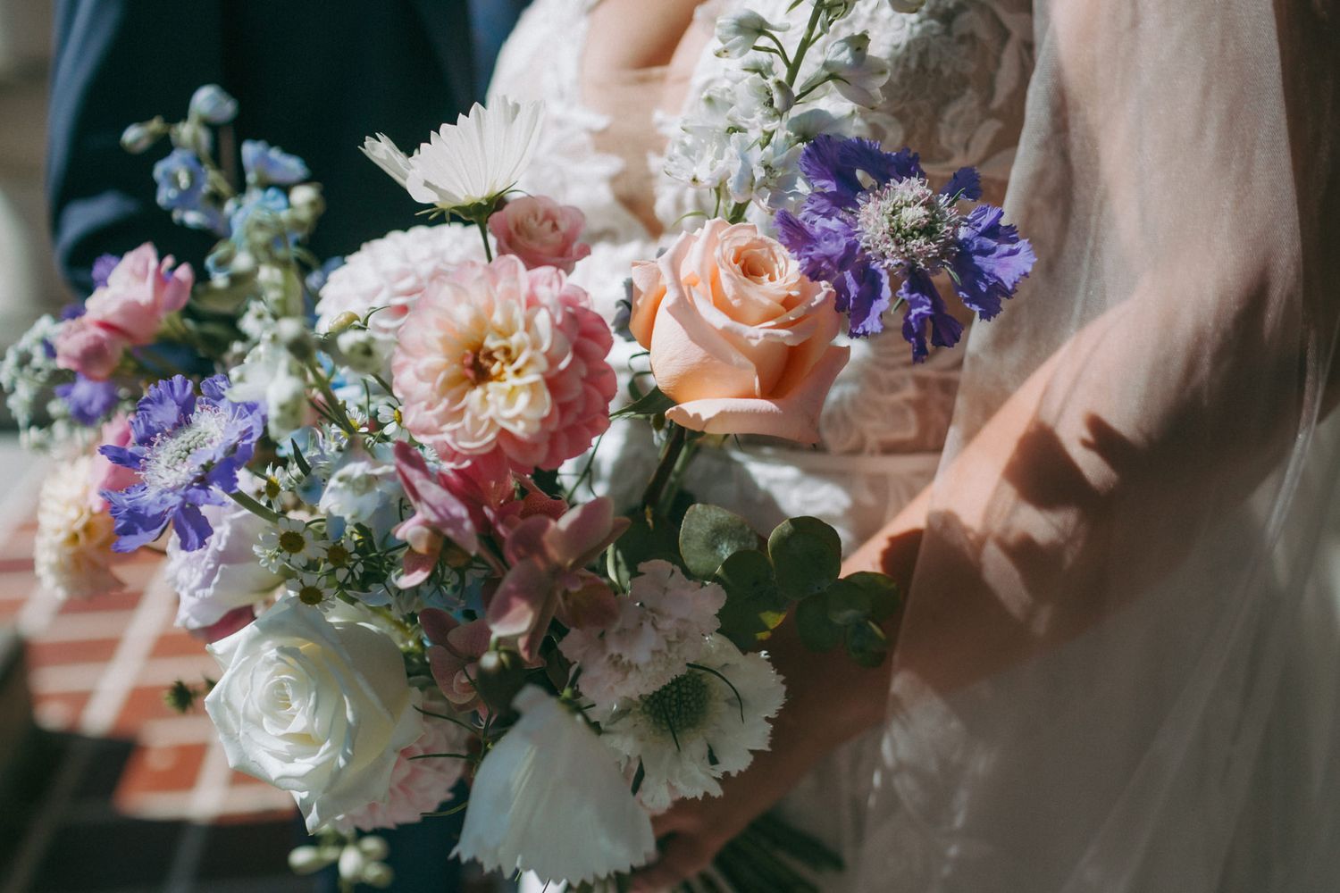 Romantic bridal bouquet featuring peach roses and purple delphinium flowers.