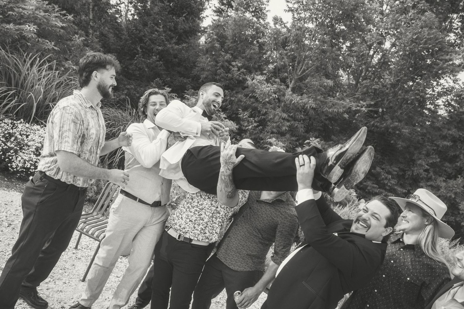 A vintage black and white photograph showing a playful group of people leaning backwards in a line outdoors.
