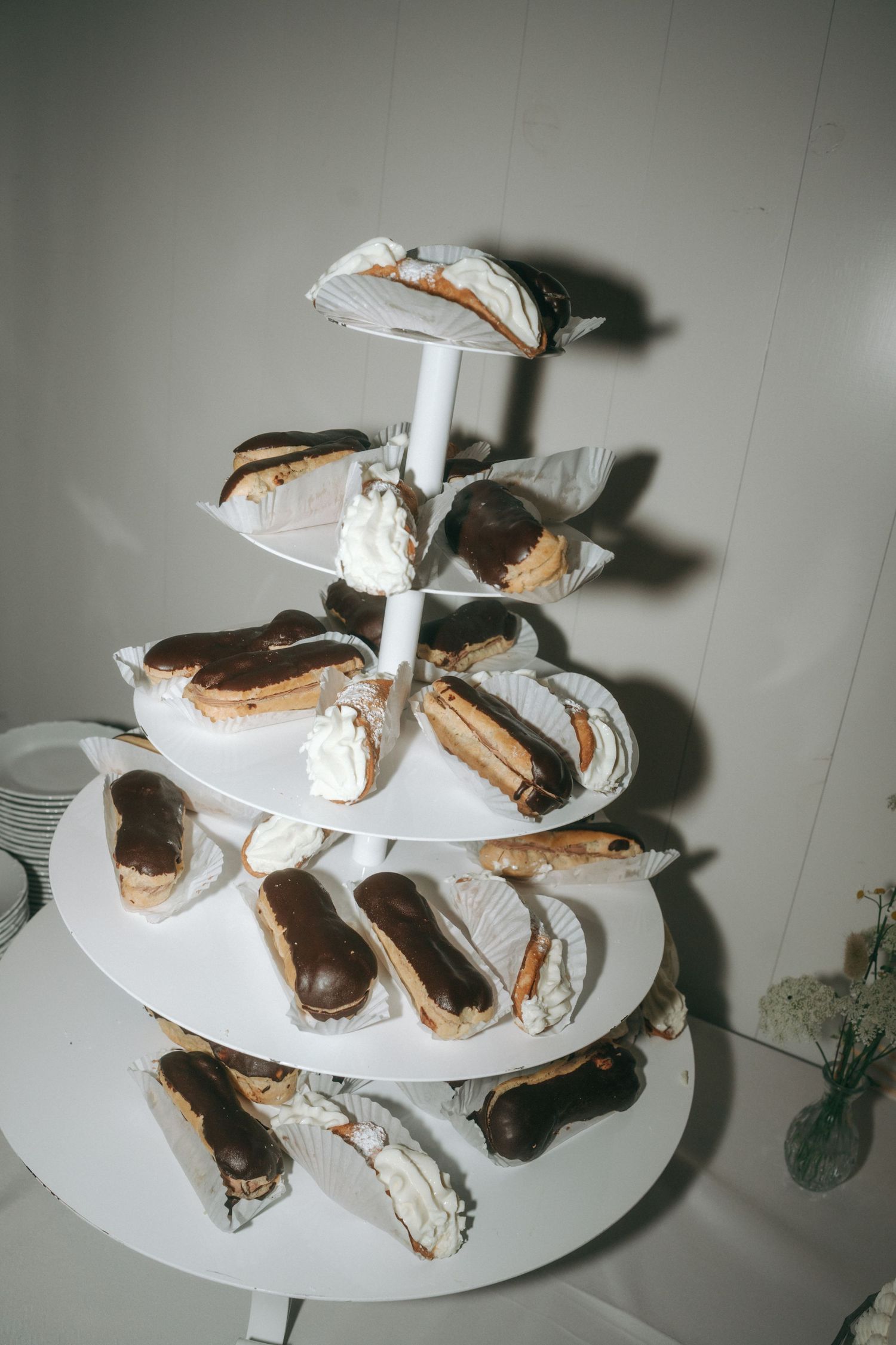 A series of chocolate-covered s'mores arranged on a white tiered display stand viewed from different angles.