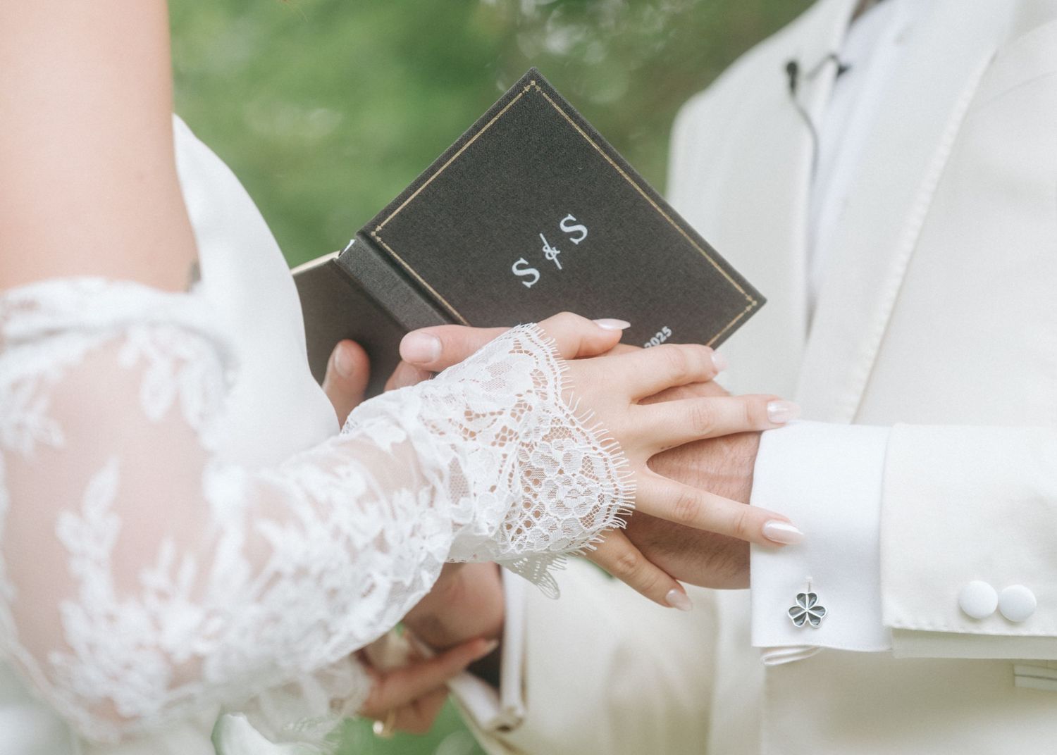 Close-up view of hands exchanging wedding rings during an outdoor garden ceremony.