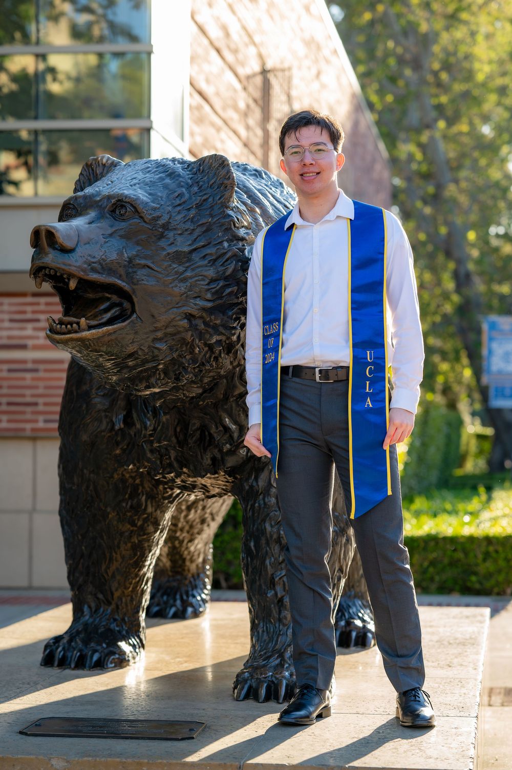 A series of photos showing a person posing with a large bronze bear statue on a university campus.