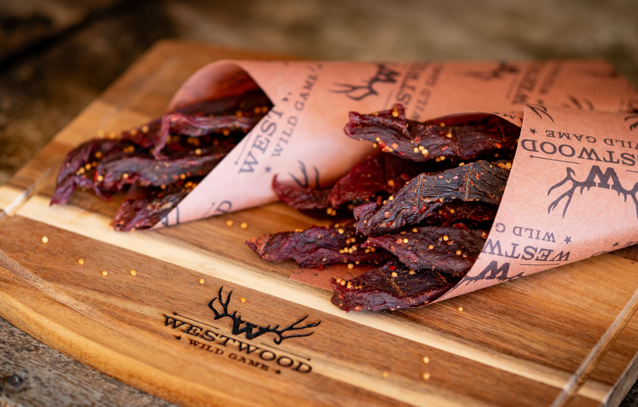 Beer bottles and packaged meat on a wooden cutting board in dim lighting.