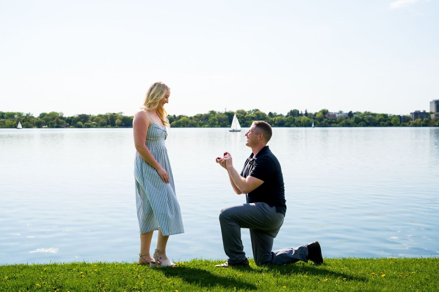 Marriage proposal moment captured by waterside with ring box.