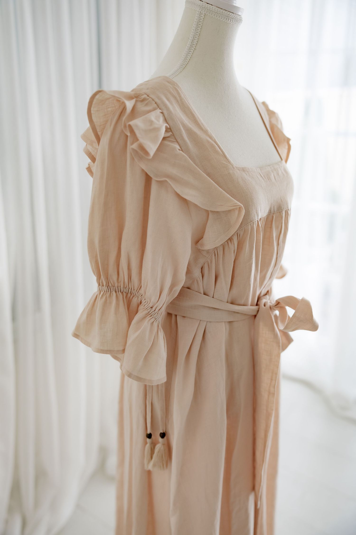Detailed view of romantic dress shoulder with ruffled sleeves and gathered waistline.