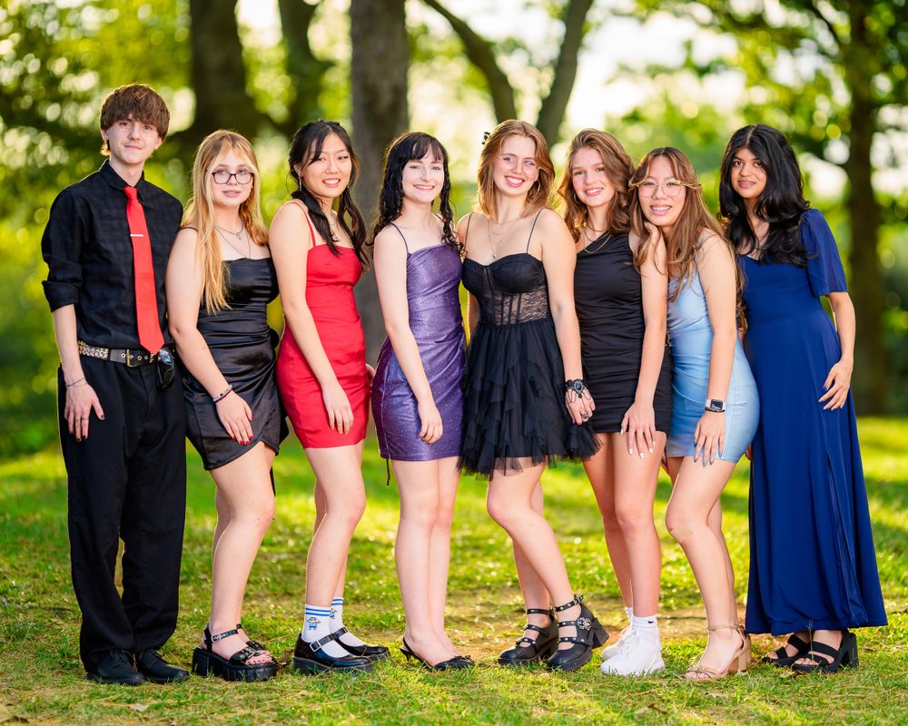 Group dressed up for formal event posing together outdoors in evening wear.