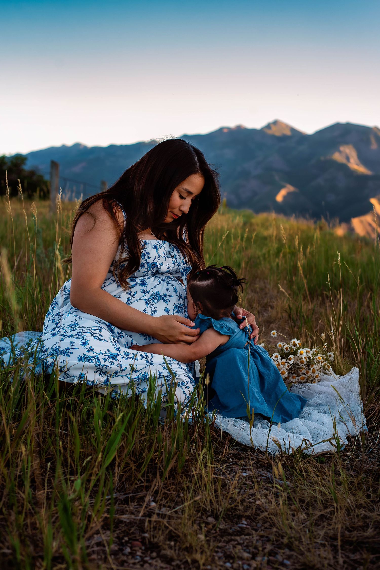 mother and daughter at a maternity session in Snow Basin, Utah the little girl is kissing her mothers belly