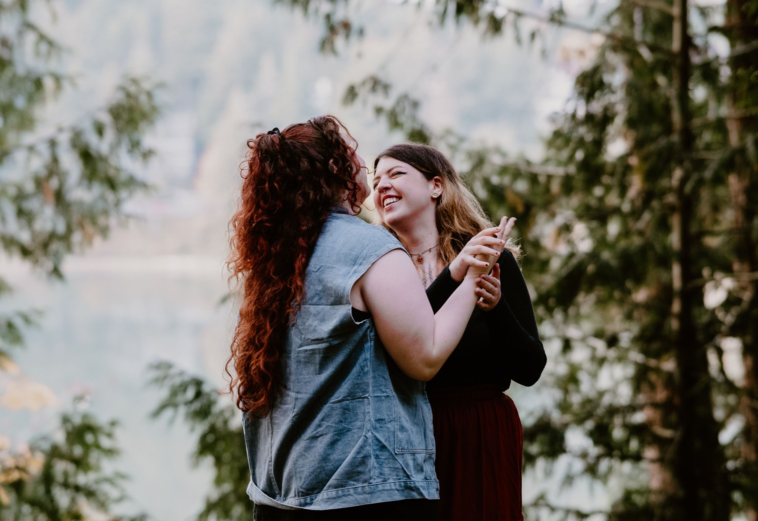 Two people in casual denim sharing a tender moment outdoors during golden hour.
