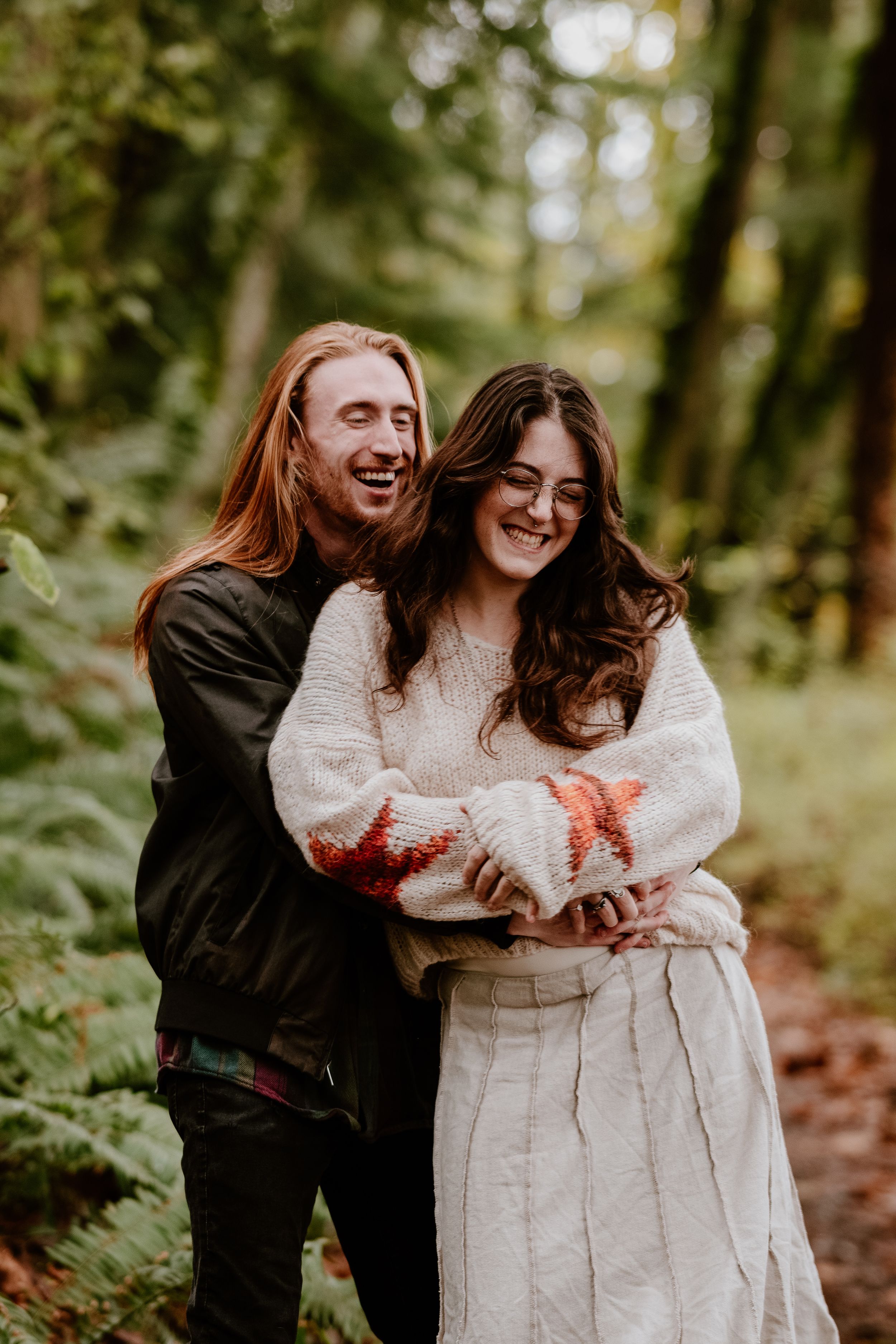 Two people laughing together in casual autumn outfits during an outdoor photoshoot.