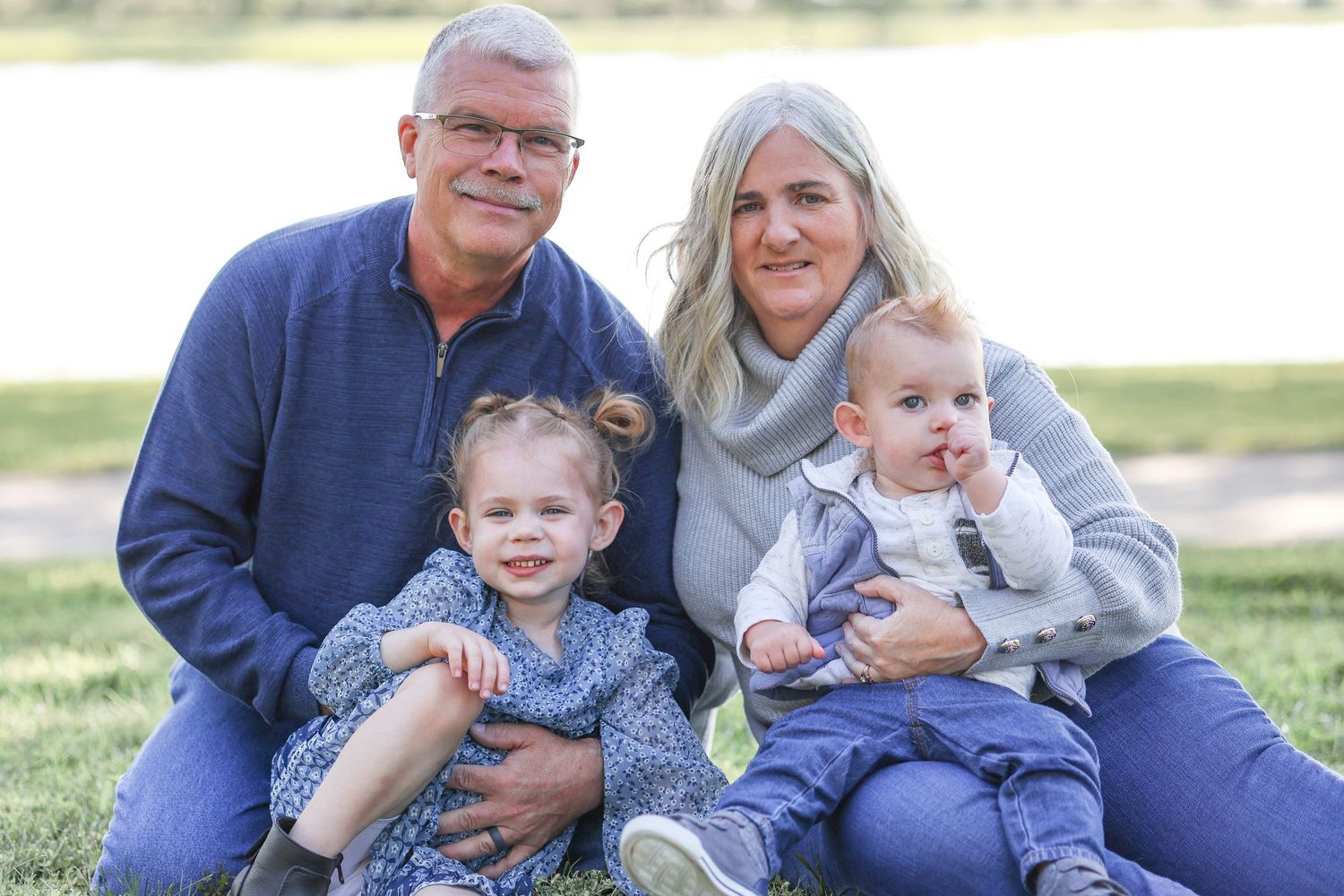 Family group sitting together on grass during outdoor photo session.