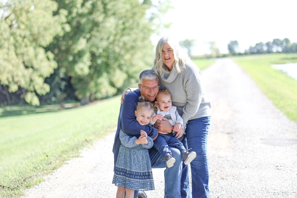 Family group embracing and laughing together on sunny outdoor path.