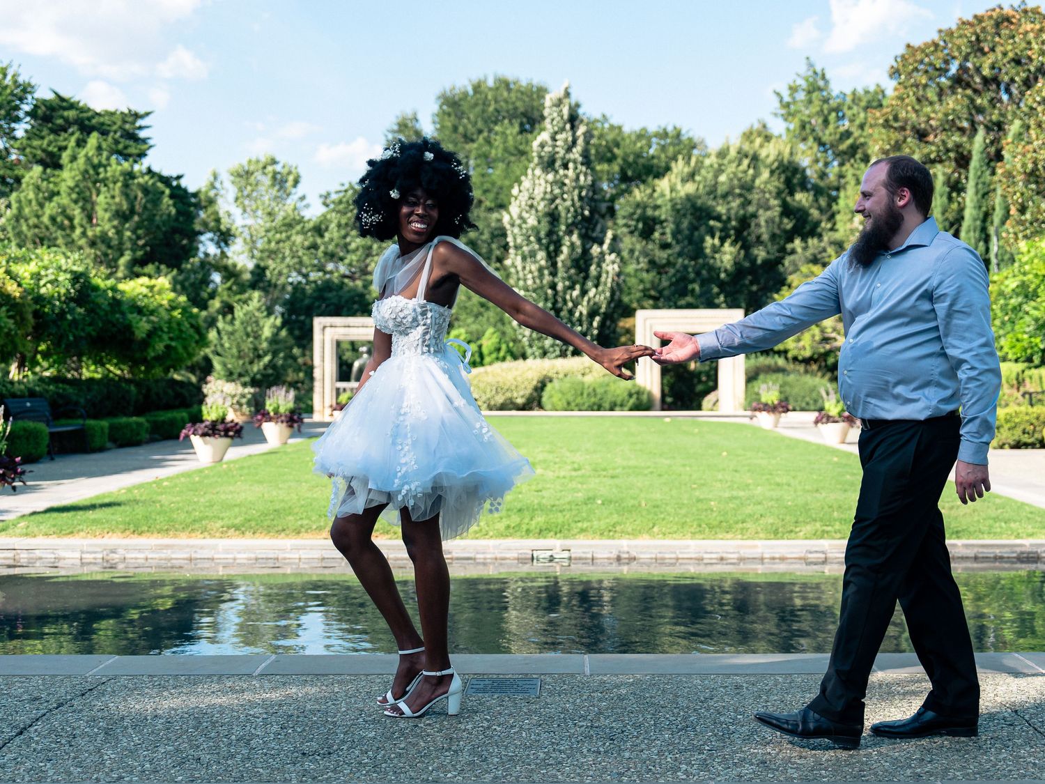 A joyful couple in wedding attire dancing together in a garden setting.