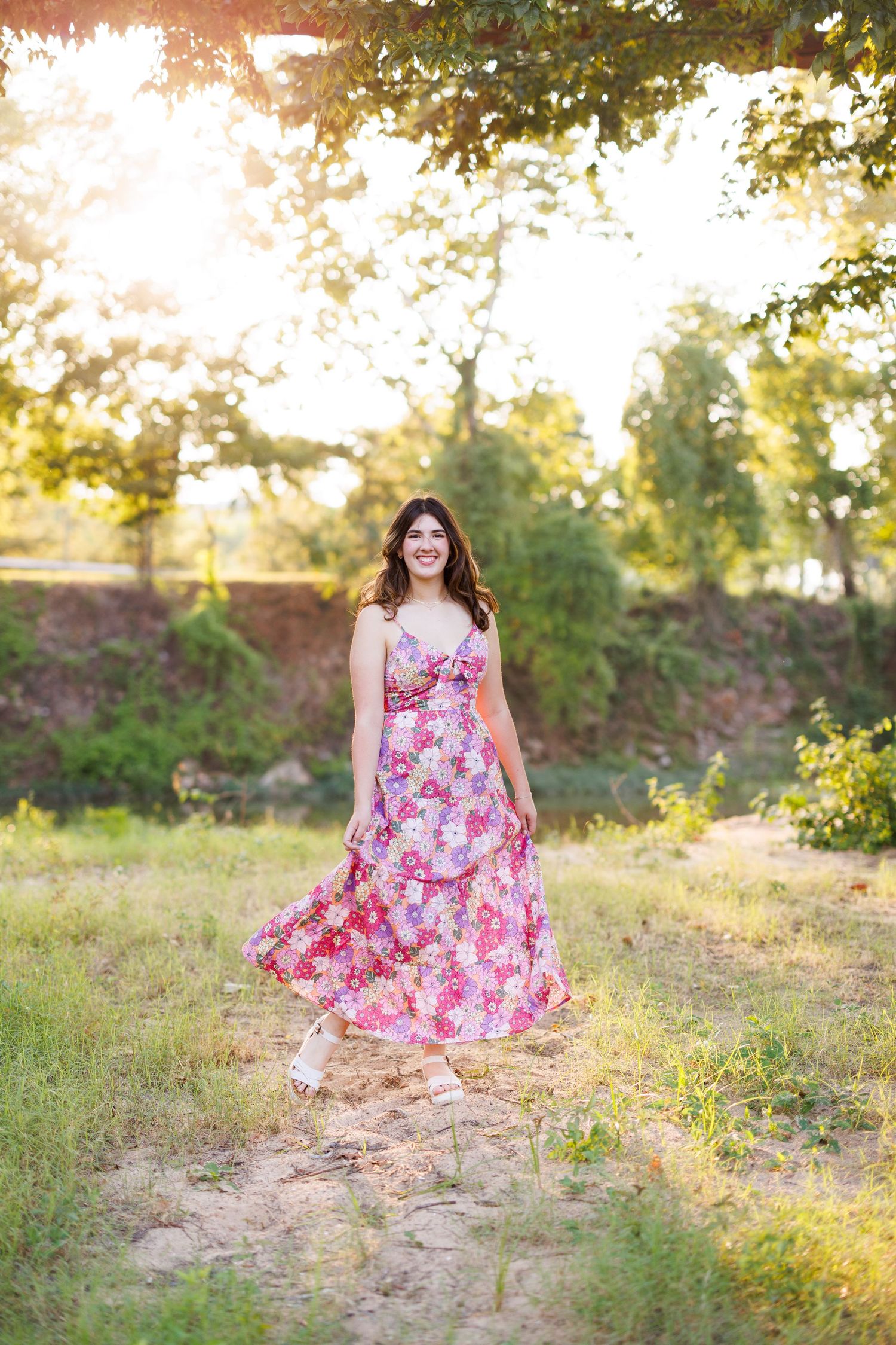 Pink floral dress stands out against a natural outdoor backdrop with warm evening light.