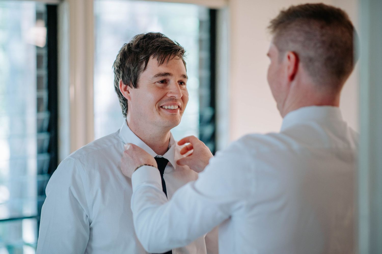 A bow tie being adjusted during wedding day preparations.