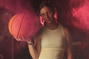 Athletic figure posing with basketball amidst dramatic pink smoke effects.