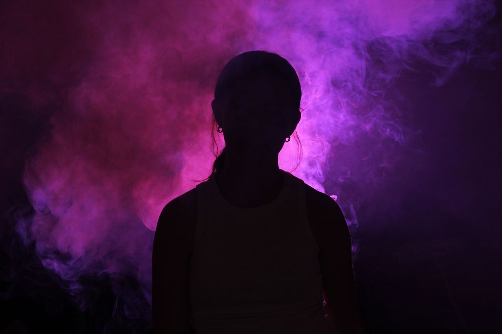 Dramatic silhouettes against a vibrant purple smoky background creating an atmospheric mood.