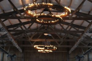 Rustic wooden ceiling beams and circular chandeliers decorated with warm glowing lights create an elegant ambiance.