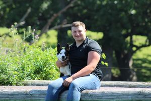 Outdoor portrait session in a park with two people and a small black and white dog.