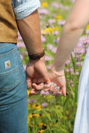 Close-up photo series of two people holding hands while walking through a wildflower field.
