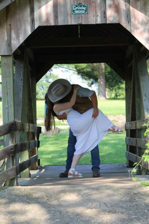 Four sequential images show someone examining beneath a covered wooden bridge, crouching down progressively lower to look underneath.