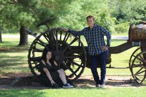 Couple sitting by antique cannons in a historic park setting.