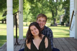 Romantic portrait under a white gazebo surrounded by green trees.