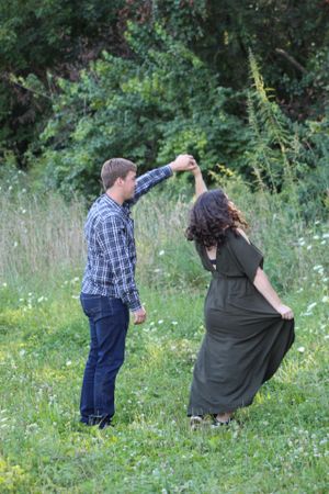 Couple sharing playful moments in a wildflower meadow during a photo shoot.