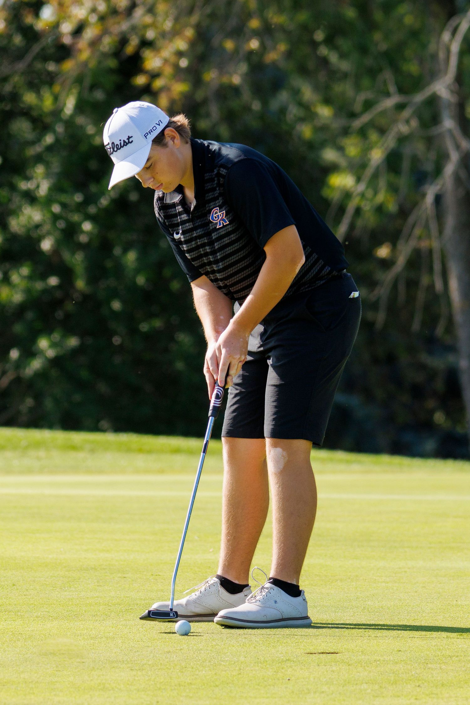 Golfers practicing putting on a sunny green course.
