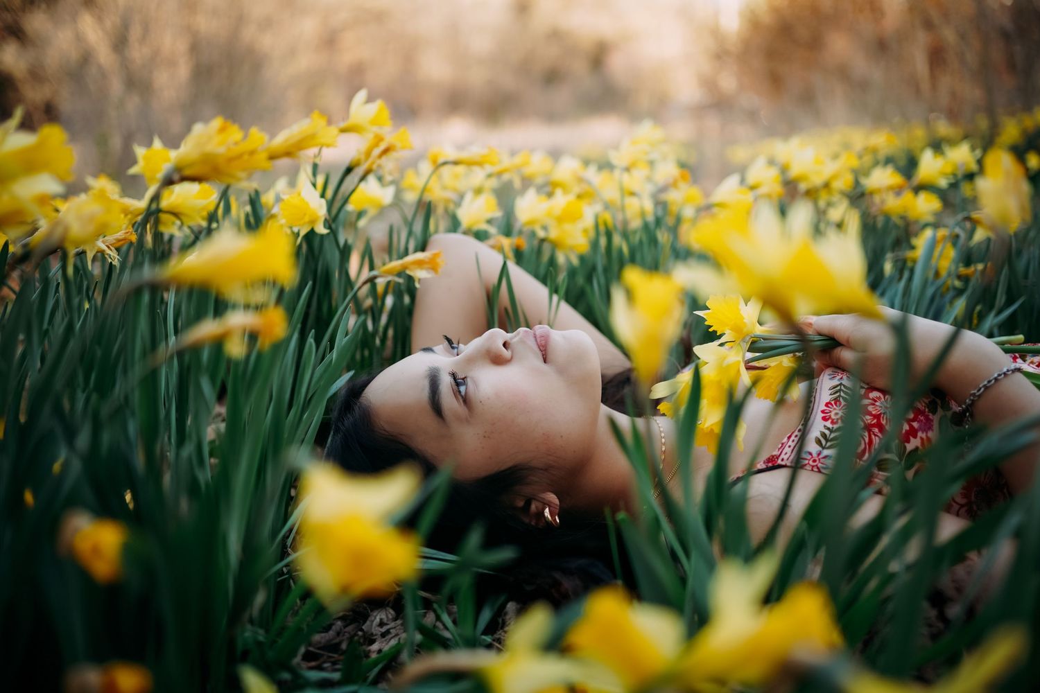 Senior photograph of young lady laying in a field of daffodils