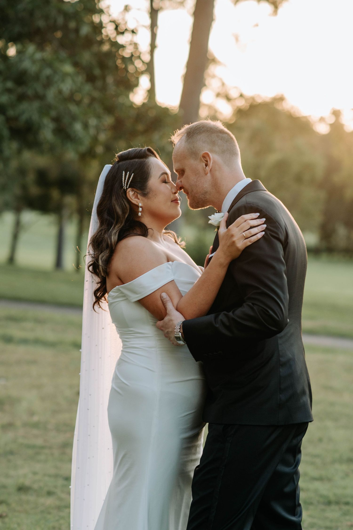 Romantic sunset portrait of newlyweds embracing in a garden setting.