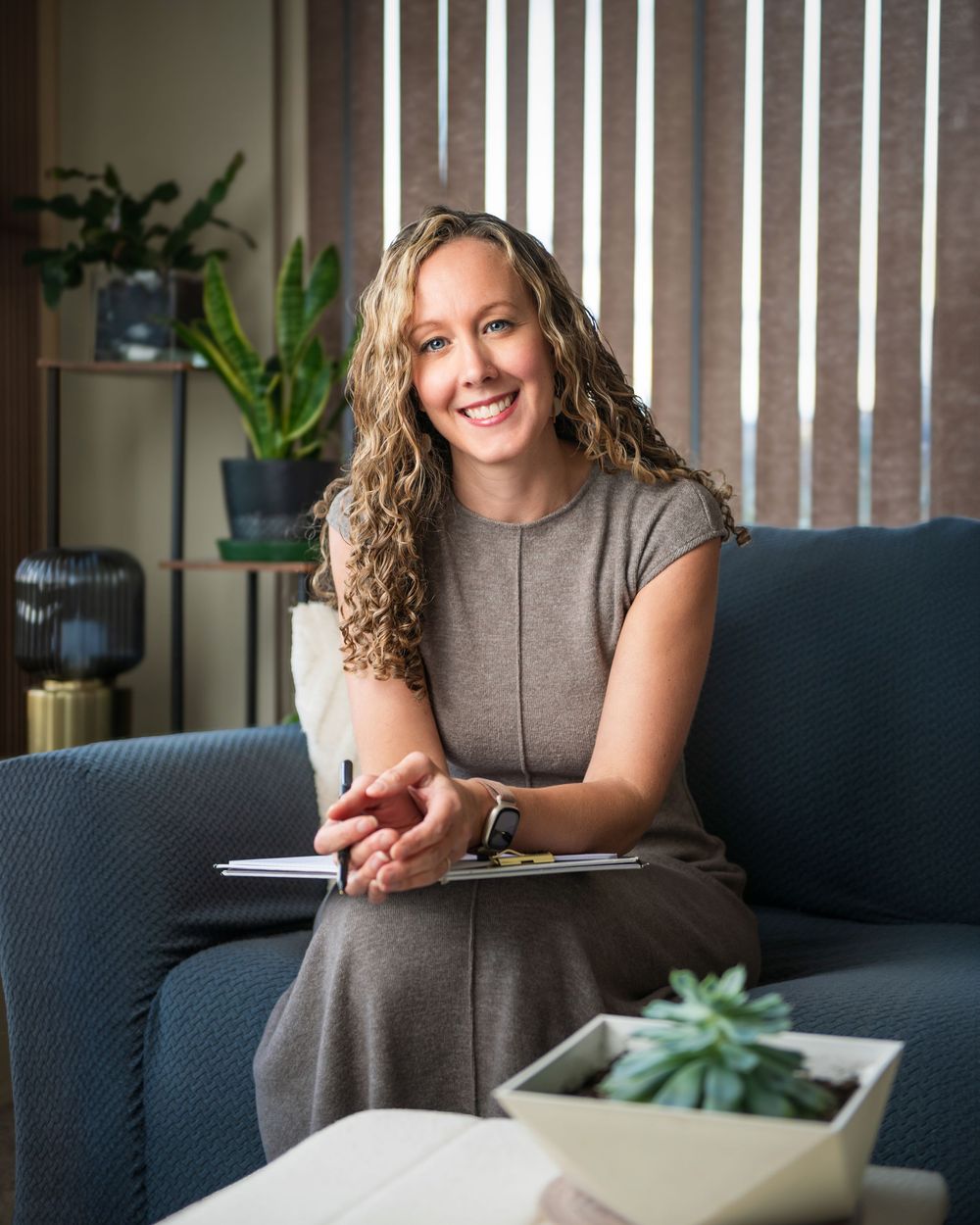 Lynne Wiseman, Kelowna counsellor, seated on a couch in her office holding a notebook, photographed by Tania Veitch Photography.