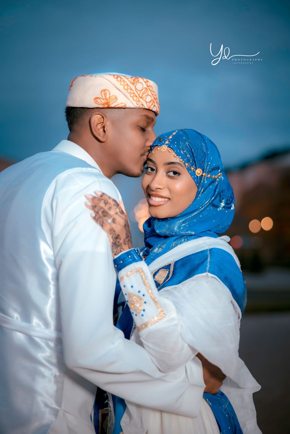 A couple in traditional Islamic dress sharing an intimate moment against a blue backdrop.