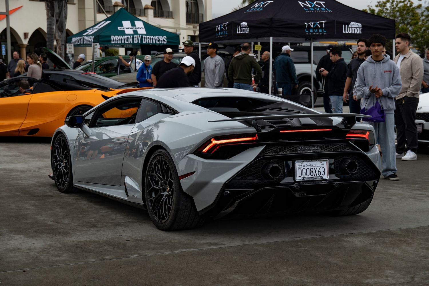 Silver Lamborghini Huracan rear view at a car show with spectators.