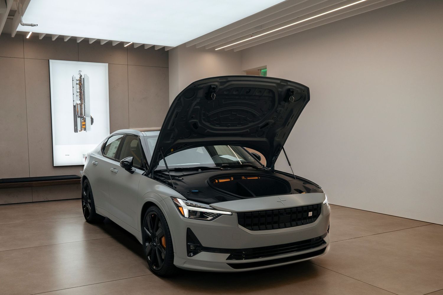 White Polestar 2 electric sedan with frunk open in a showroom.