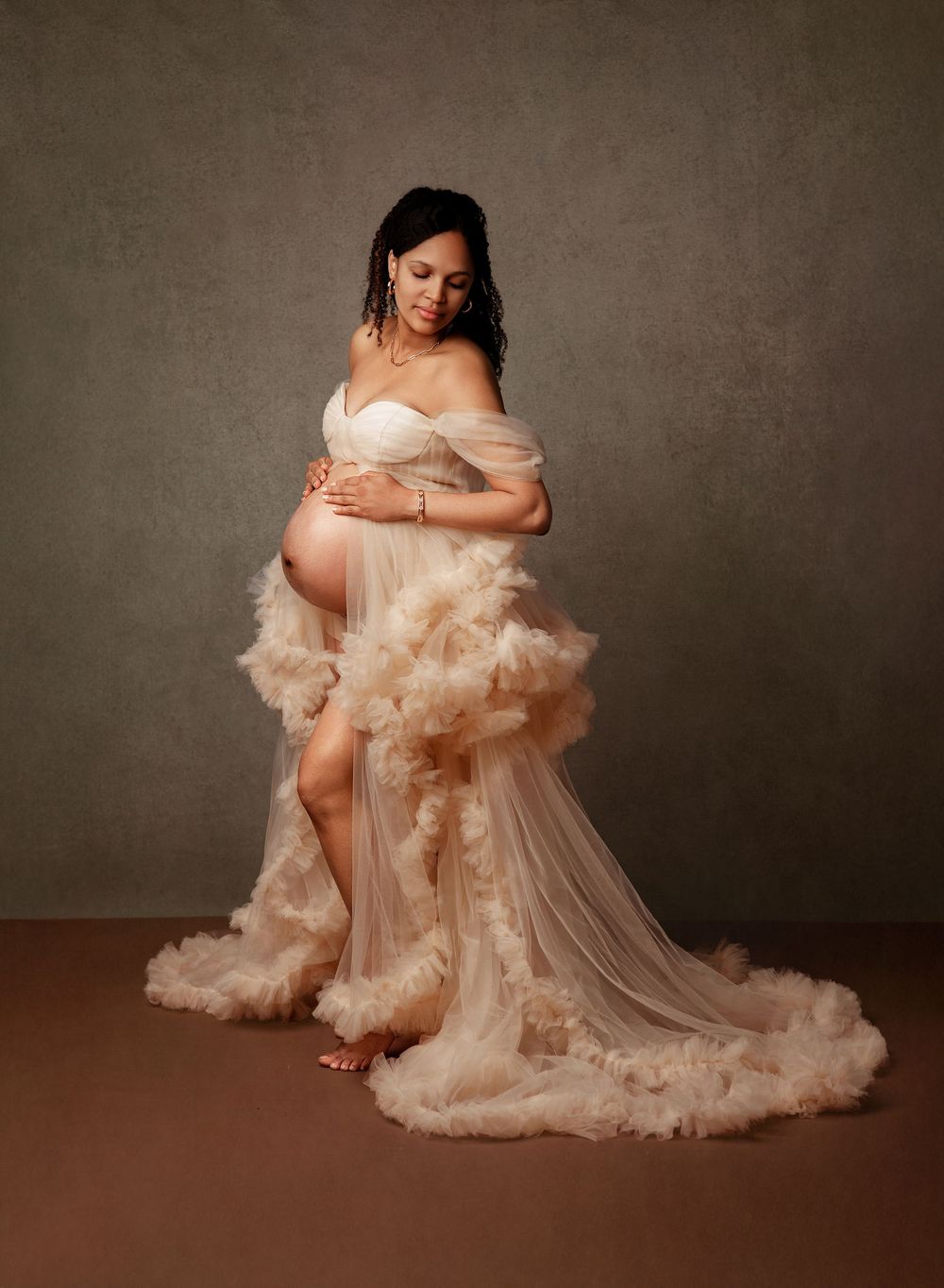 Ethereal maternity photo series in blush tones featuring flowing tulle gowns and romantic studio lighting.