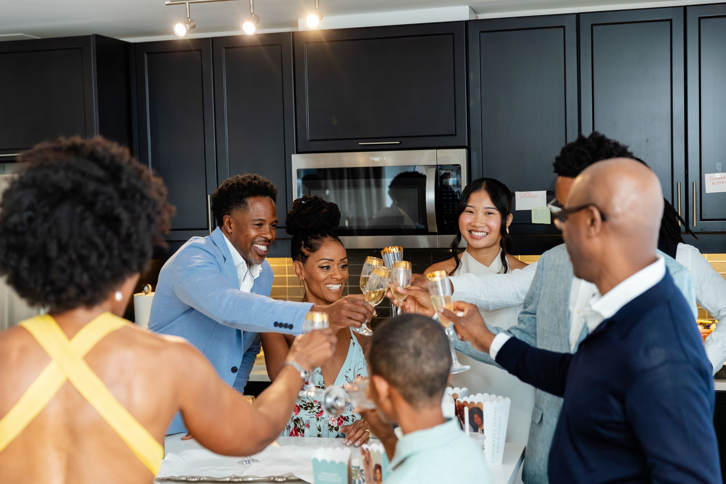 Group of people enjoying a social gathering in a modern kitchen with overhead lighting.