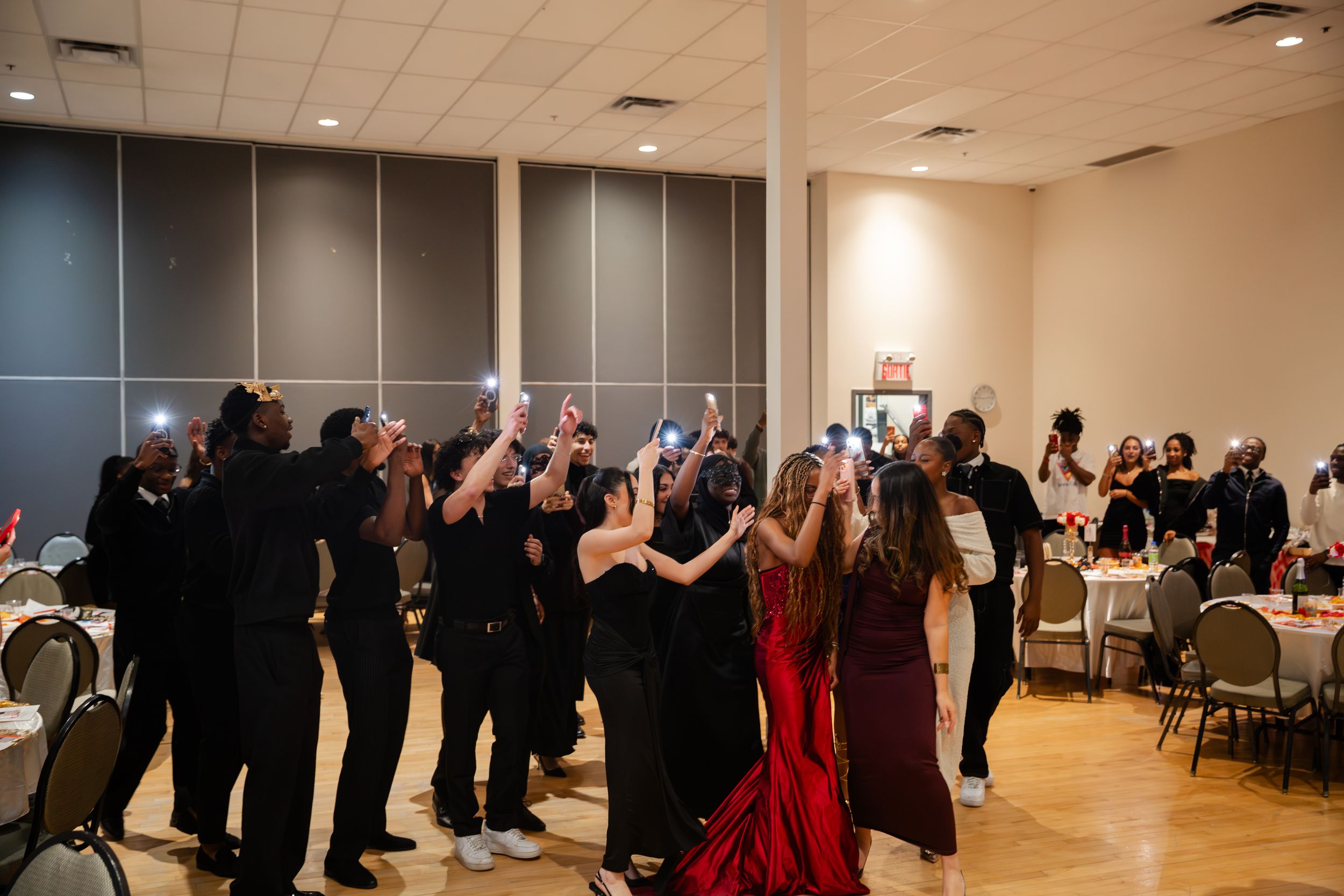 Party guests in formal attire dancing and celebrating together in a banquet hall during an evening event.